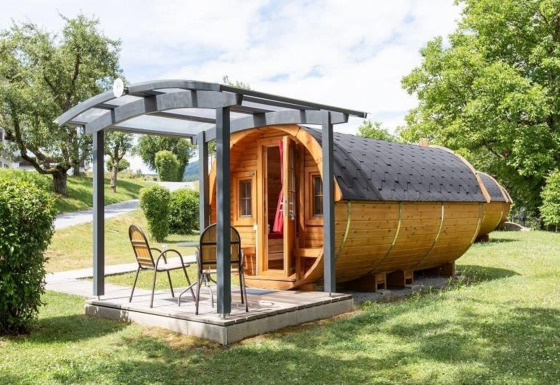 Casa diminuta Tractor cabin de madera con terraza y sillas en un entorno verde y natural.