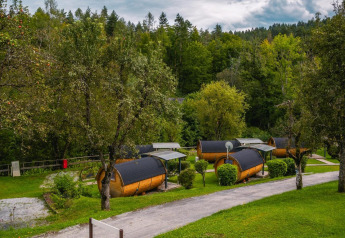 Traktorhytter ved Wörthersee i Østrig, omgivet af grønne træer og frodig natur under en overskyet himmel.