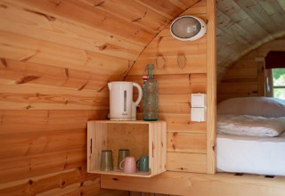 Acogedor interior de madera en una tiny house con hervidor, vasos y cama en Tractor cabin, Wörthersee, Austria.