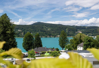 Vista sul lago Wörthersee in Austria con alberi verdi, caravan e acqua azzurra dalla Tractor cabin.