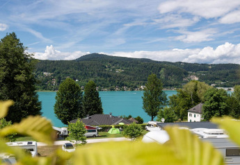 Udsigt over den smukke Wörthersee i Østrig med grønne træer, sø og campingvogne ved tractor cabin.