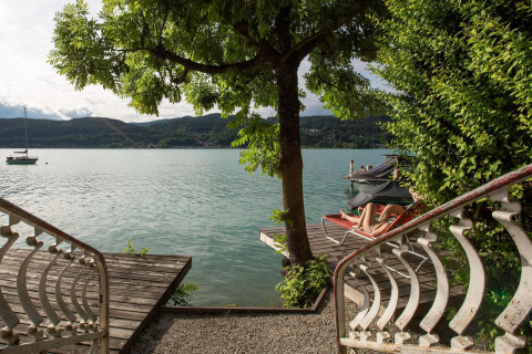 Vista desde la pequeña Tractor Cabin en Wörthersee, Austria, con lago, árbol y persona relajándose.