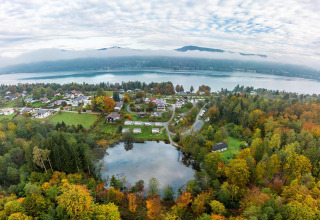 Vista aérea de la Tractor Cabin y tiny houses en Wörthersee, Austria, rodeadas de bosque y lago pintoresco.