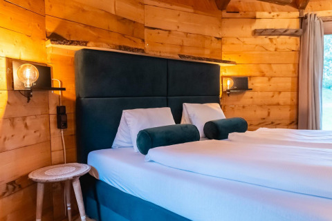Acogedor dormitorio en Treehouse at Wörthersee, Austria, con paredes de madera, cama doble y luz suave.