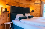 Acogedor dormitorio en Treehouse at Wörthersee, Austria, con paredes de madera, cama doble y luz suave.