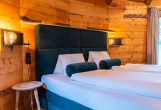 Acogedor dormitorio en Treehouse at Wörthersee, Austria, con paredes de madera, cama doble y luz suave.