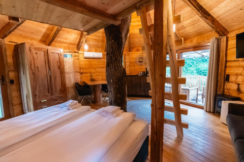 Acogedor interior de la Treehouse en Wörthersee, Austria, con decoración de madera y puerta acristalada grande.