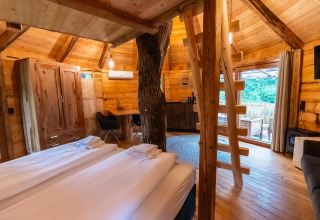 Acogedor interior de la Treehouse en Wörthersee, Austria, con decoración de madera y puerta acristalada grande.