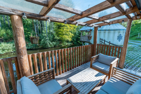 Terraza de madera con muebles y vistas al río en Treehouse at Wörthersee, Austria, ambiente natural.