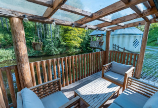 Terraza de madera con muebles y vistas al río en Treehouse at Wörthersee, Austria, ambiente natural.