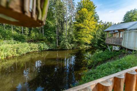 Udsigt over en sø og skov fra en træhytte ved Wörthersee i Østrig, med sollys gennem trætoppene.
