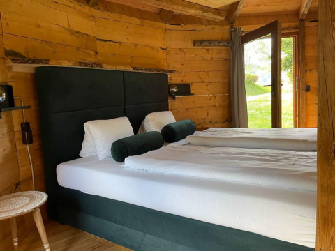 Dormitorio acogedor en una tiny house Treehouse en Wörthersee, Austria, con paredes de madera y vista al jardín.