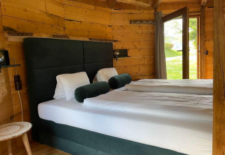 Dormitorio acogedor en una tiny house Treehouse en Wörthersee, Austria, con paredes de madera y vista al jardín.
