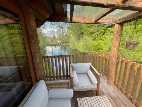 Vista desde la casa del árbol en Wörthersee, Austria, con balcón de madera y estanque natural.
