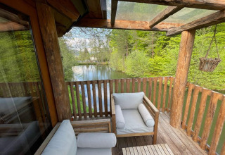 Vista desde la casa del árbol en Wörthersee, Austria, con balcón de madera y estanque natural.