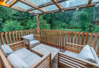Terraza de madera con cómodos asientos y vistas al bosque junto al Treehouse at Wörthersee en Austria.