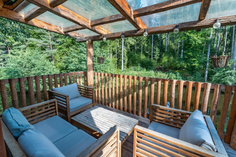 Terraza de casa del árbol en Wörthersee, Austria, con asientos cómodos y vista al bosque verde.