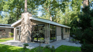 Vue extérieure du lodge Hackfort MIVA à De Utrechtse Heuvelrug, Pays-Bas, entouré d’arbres et terrasse.