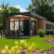 Moderne lodge ved Cannenburch, Veluwepark de Bosgraaf, med terrasse, parasol og frodig have i Holland.