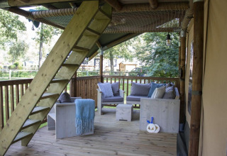 Terrazza coperta in legno con arredamento rustico e scala presso una tenda safari al Veluwepark de Bosgraaf, Paesi Bassi.