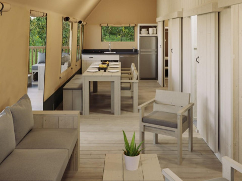 Interior de carpa safari Ranger Lodge en Veluwepark de Bosgraaf, Países Bajos, con muebles de madera rústicos.