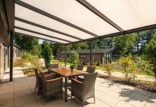 Terraza cubierta con mesa y sillas en Veluwe Lodge, Veluwepark de Bosgraaf, Países Bajos.