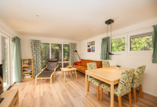 Lichte leefruimte in Veluwe Lodge bij Veluwepark de Bosgraaf, Nederland, met eetruimte, zitbank en grote ramen.