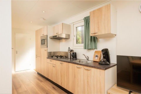 Cocina moderna en Veluwe Lodge en Veluwepark de Bosgraaf, Países Bajos, con armarios de madera y electrodomésticos.