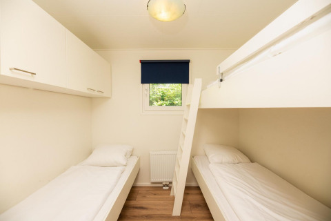 Dormitorio luminoso en Veluwe Lodge, Veluwepark de Bosgraaf, Países Bajos, con litera y cama individual.
