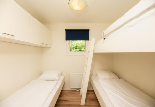 Dormitorio luminoso en Veluwe Lodge, Veluwepark de Bosgraaf, Países Bajos, con litera y cama individual.