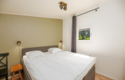 Bedroom at Forest Lodge, Veluwepark de Bosgraaf in the Netherlands, featuring a double bed and small window.