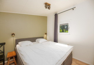 Dormitorio en Forest Lodge en Veluwepark de Bosgraaf, Países Bajos, con cama doble y ventana pequeña.