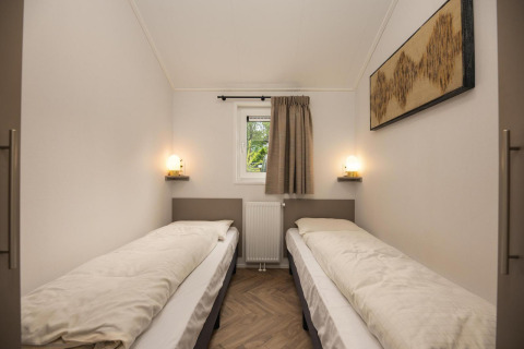 Habitación doble con dos camas en Lodge Loevestein del Veluwepark de Bosgraaf, Países Bajos, decoración simple.