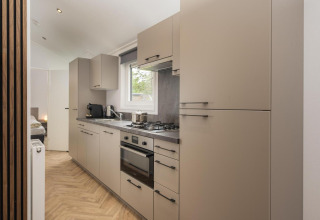 Moderne Küchenzeile mit beigen Schränken im Lodge Loevestein, Veluwepark de Bosgraaf, Niederlande.