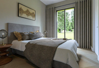 Modernes Schlafzimmer in der Loevestein-Lodge im Veluwepark de Bosgraaf in den Niederlanden mit Gartenblick.
