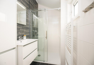Modernes Badezimmer mit Glasdusche, weißer Einrichtung und dunkler Wand in Velthorst, Veluwepark de Bosgraaf.