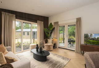 Soggiorno della lodge Loevestein Comfort al Veluwepark de Bosgraaf nei Paesi Bassi, con arredi moderni e vista sul giardino.