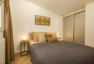 Acogedor dormitorio de lodge con cama doble, cojines elegantes, lámparas de noche y arte moderno.