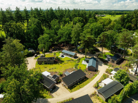 Vista aérea de la lodge Loevestein Comfort en Veluwepark de Bosgraaf, Países Bajos, rodeada de bosques verdes.