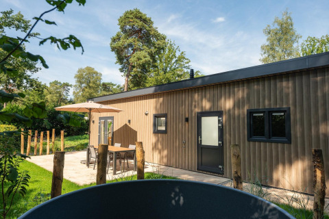Lodge Loevestein con jacuzzi en Veluwepark de Bosgraaf, Países Bajos, rodeado de naturaleza y terraza moderna.