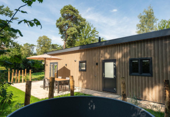 Luksus lodge Loevestein med spabad på Veluwepark de Bosgraaf, Holland, omgivet af natur og skov.