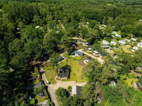 Vista aérea del lodge Loevestein con jacuzzi en Veluwepark de Bosgraaf, Países Bajos, rodeado de bosque.