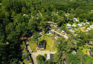 Vista aérea del lodge Loevestein con jacuzzi en Veluwepark de Bosgraaf, Países Bajos, rodeado de bosque.