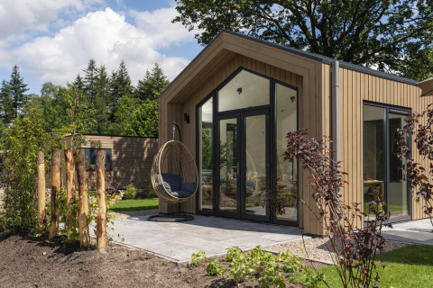 Tiny Lodge de diseño moderno con silla colgante en la terraza en Veluwepark de Bosgraaf, Países Bajos.