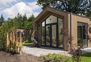 Tiny Lodge de diseño moderno con silla colgante en la terraza en Veluwepark de Bosgraaf, Países Bajos.