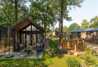 Pequeño lodge con jacuzzi exterior en Veluwepark de Bosgraaf, Países Bajos, rodeado de naturaleza y árboles.