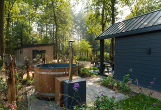 Baño de hidromasaje exterior y pequeña cabaña moderna en Veluwepark de Bosgraaf, rodeados de naturaleza en Países Bajos.