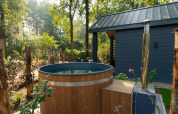 Houten buitenspa naast een moderne lodge in het groene Veluwepark de Bosgraaf in Nederland.