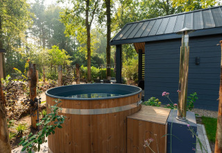 Bañera de hidromasaje de madera al aire libre junto a una cabaña moderna en Veluwepark de Bosgraaf, Países Bajos.