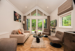 Sala de estar moderna y acogedora en Tiny Loft, con grandes ventanales en Veluwepark de Bosgraaf, Países Bajos.